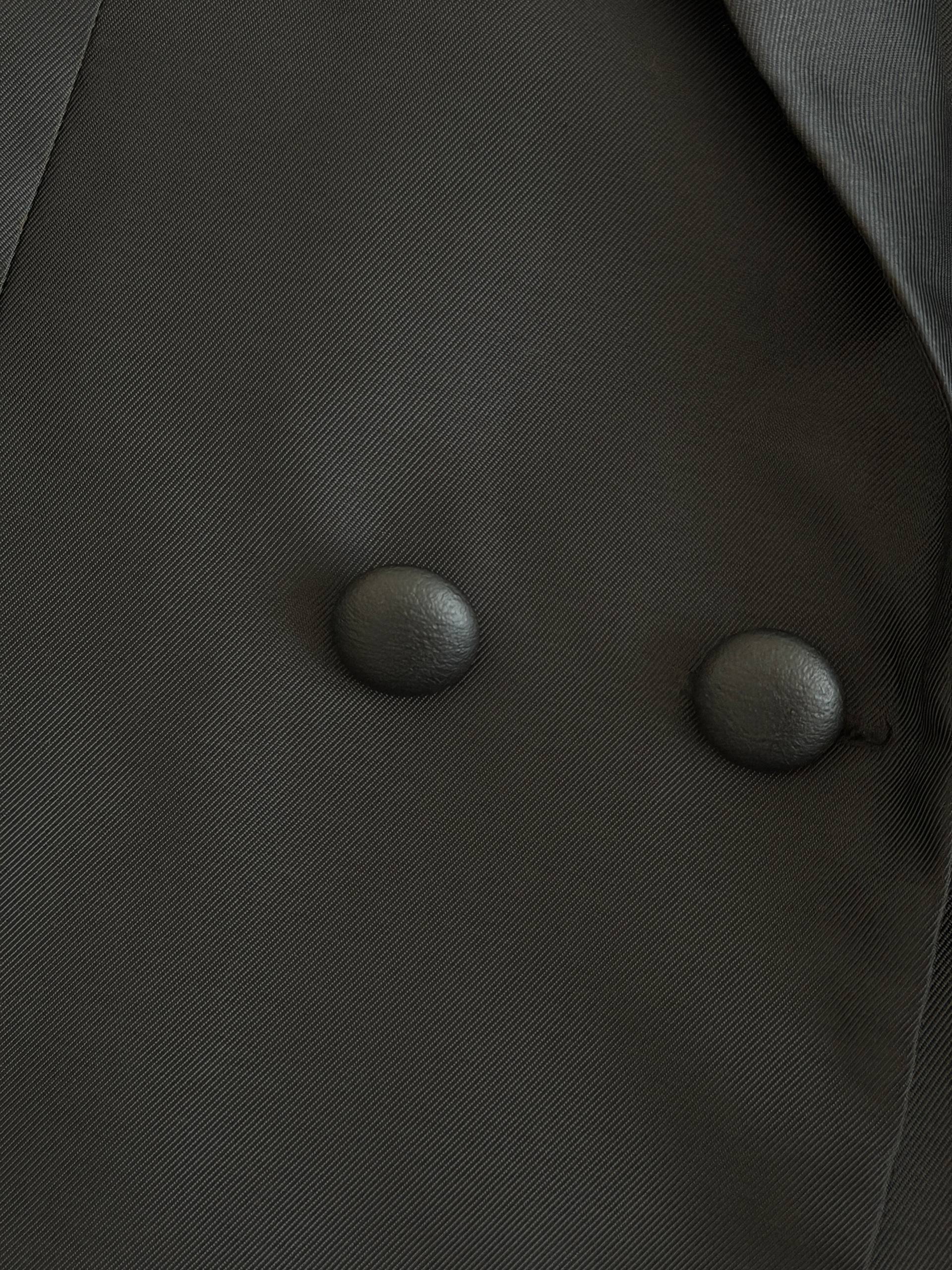 Close-up of a black fabric with two round buttons. The buttons are black and appear to be made of a shiny material. The