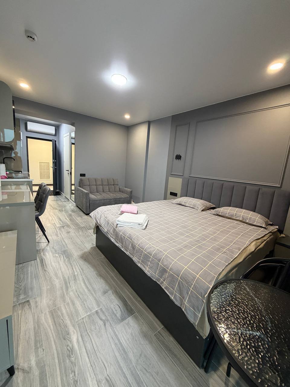 Modern and spacious bedroom with a large bed in the center. The bed has a gray headboard and is covered with a gray and
