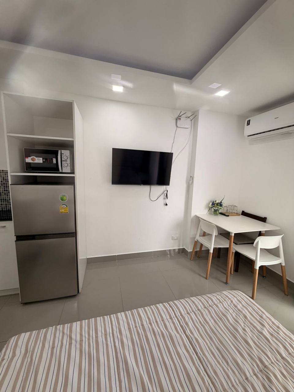 Modern and spacious bedroom with a large window on the right side. The window has sheer curtains that let in natural light.