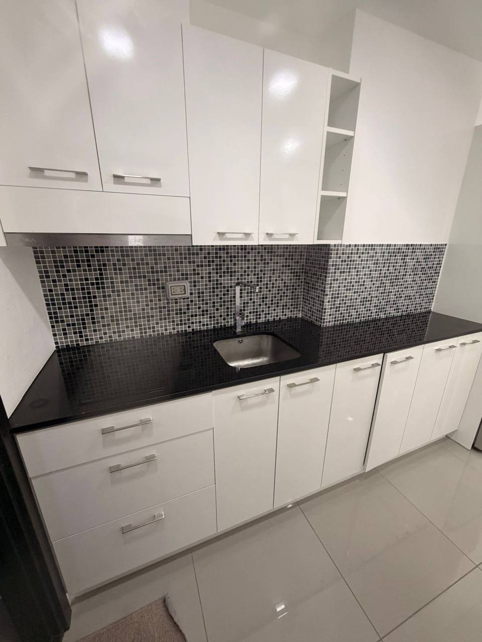 Small kitchen and dining area in a small apartment. The kitchen has a stainless steel refrigerator, a microwave, and a small