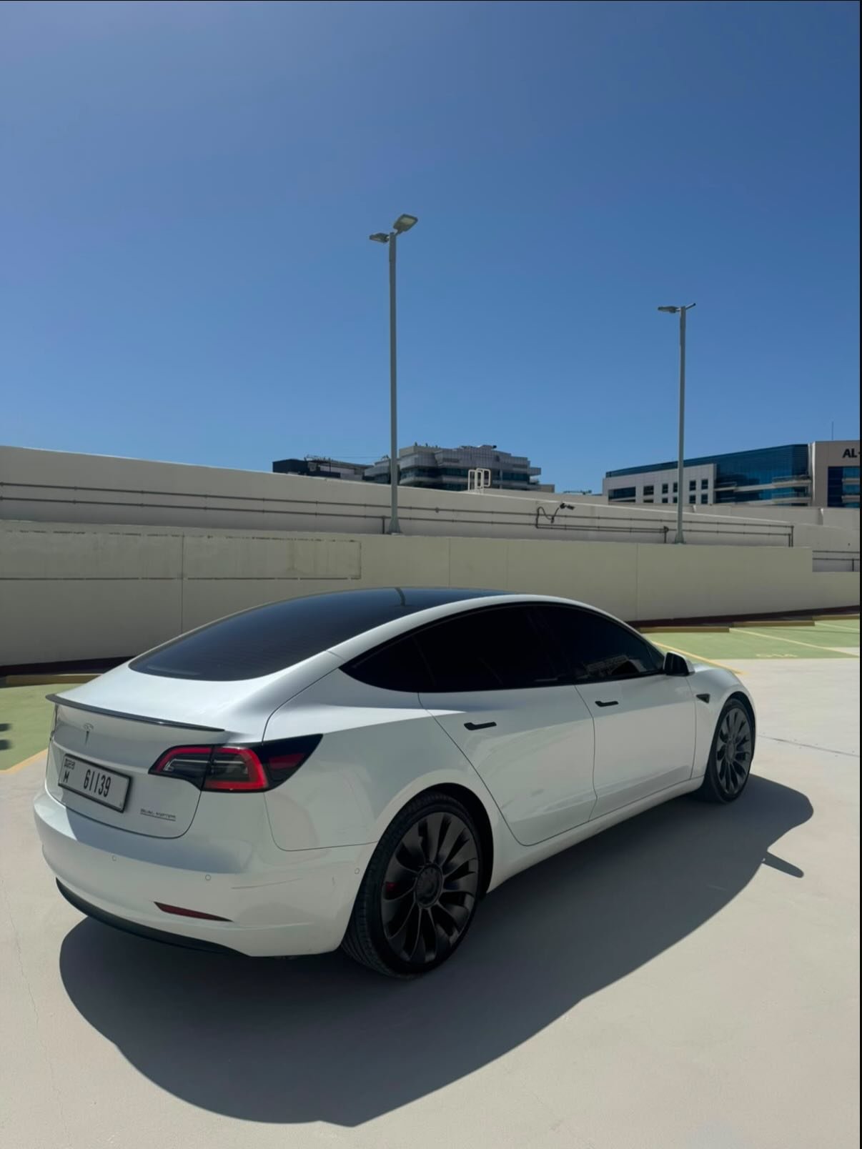 White Tesla Model S car parked on a concrete surface. The car is facing towards the right side of the image and is