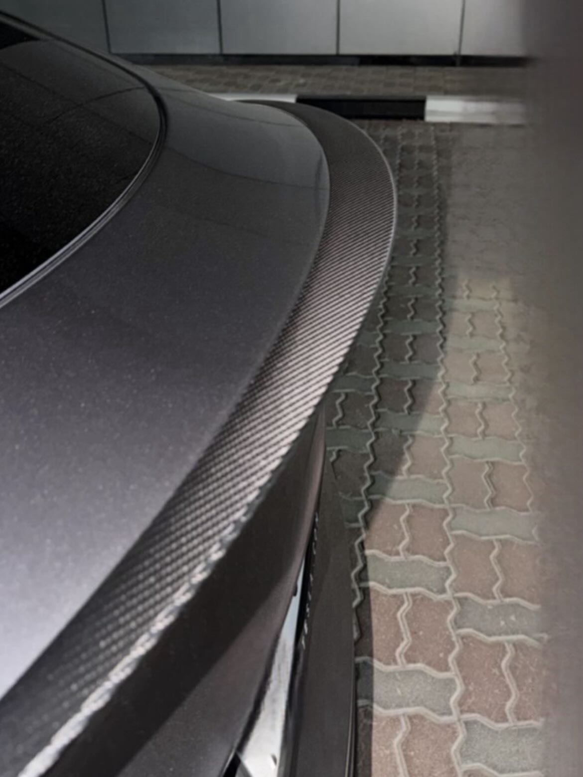 Close-up of the rear end of a black car. The car appears to be a modern model with a sleek and sporty design. The hood of