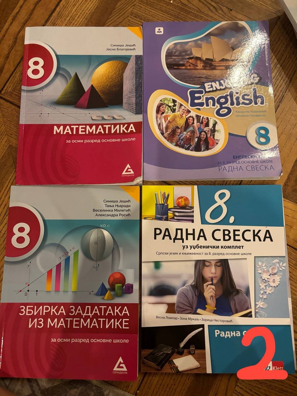 Four books arranged in a row on a wooden surface. The books are arranged in two rows of three, with the top row being the