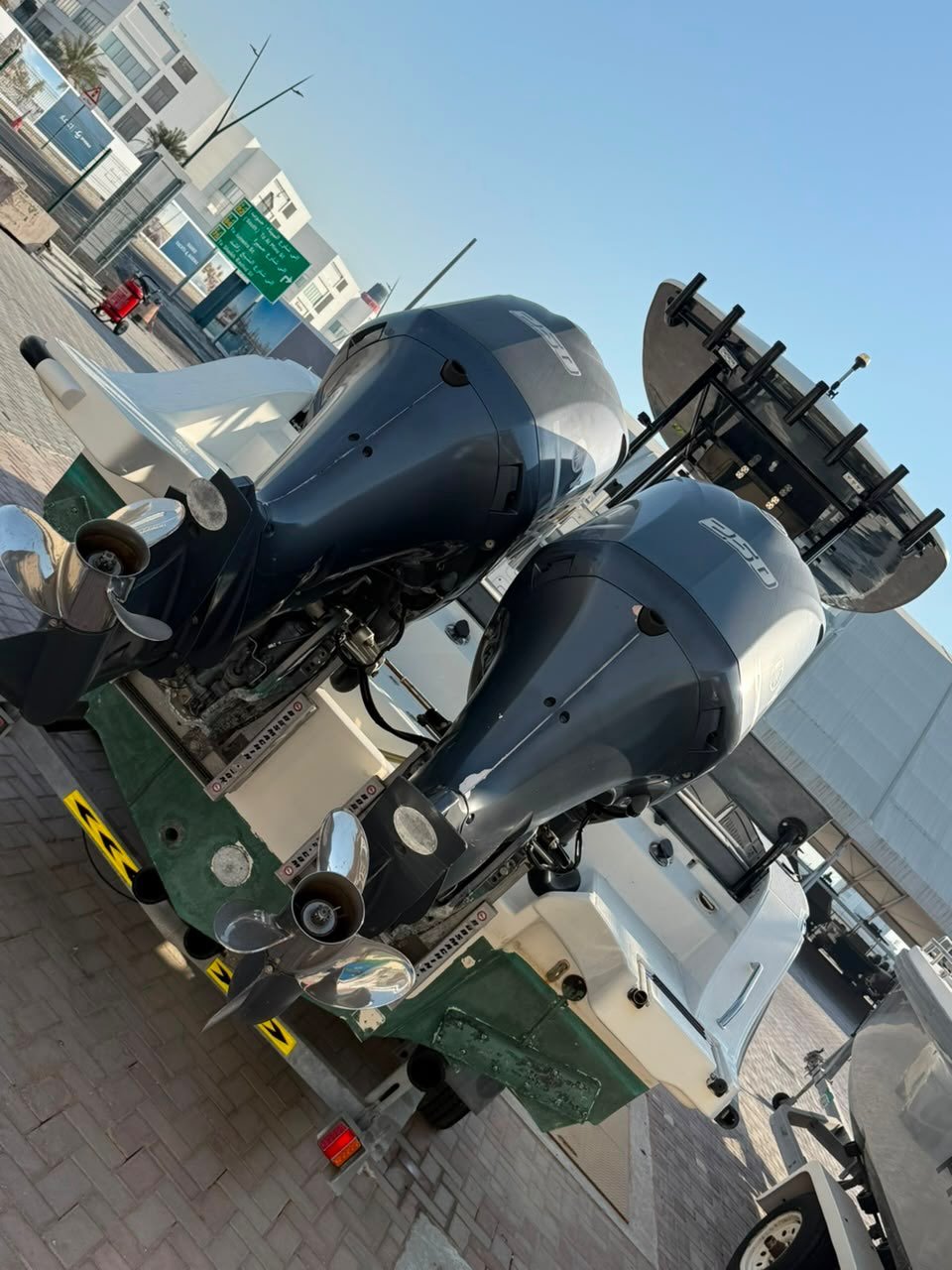 Two black outboard motors mounted on a green and white boat. The motors are mounted on the back of the boat, which is parked
