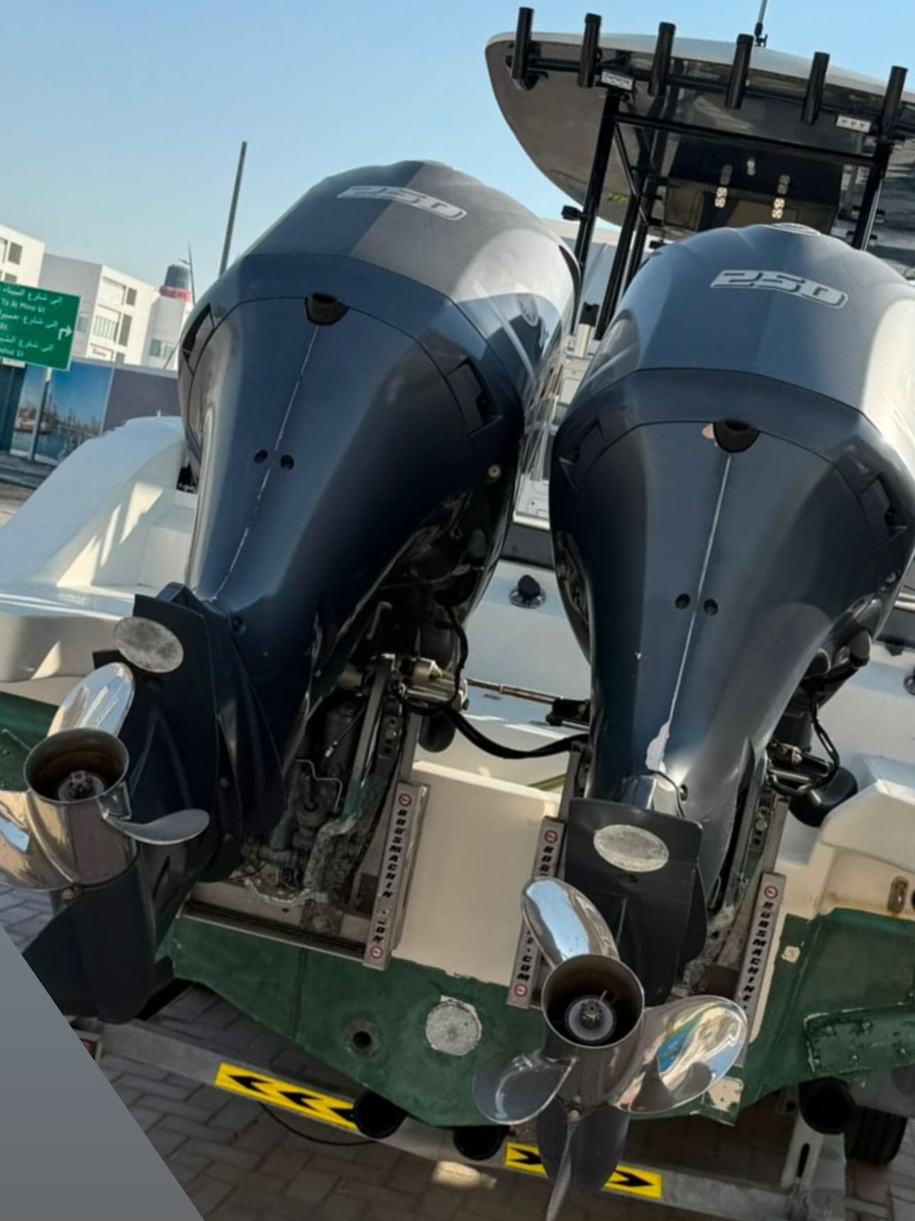 Two black outboard motors mounted on a green and white boat. The motors are mounted on the back of the boat, which is parked