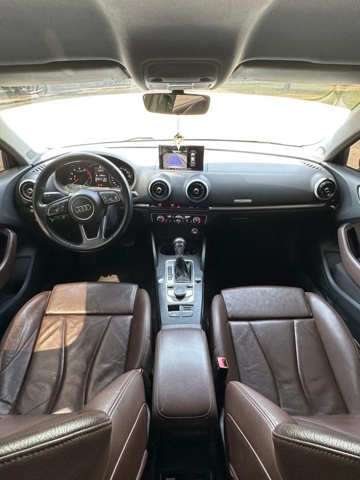 Interior of a car, specifically the driver's seat and dashboard. The car appears to be a newer model, with a black leather