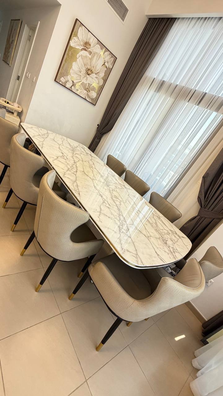 Modern dining room with a large rectangular table in the center. The table is made of white marble with a black base and has