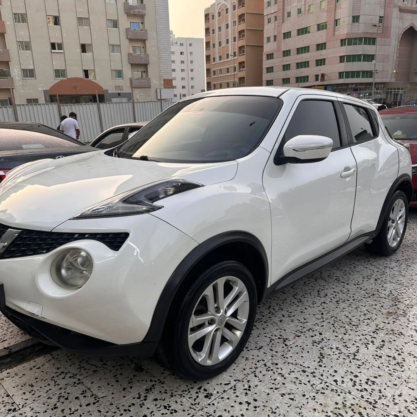 White Nissan Juke SUV parked in a parking lot. The car is facing towards the left side of the image and is positioned in the