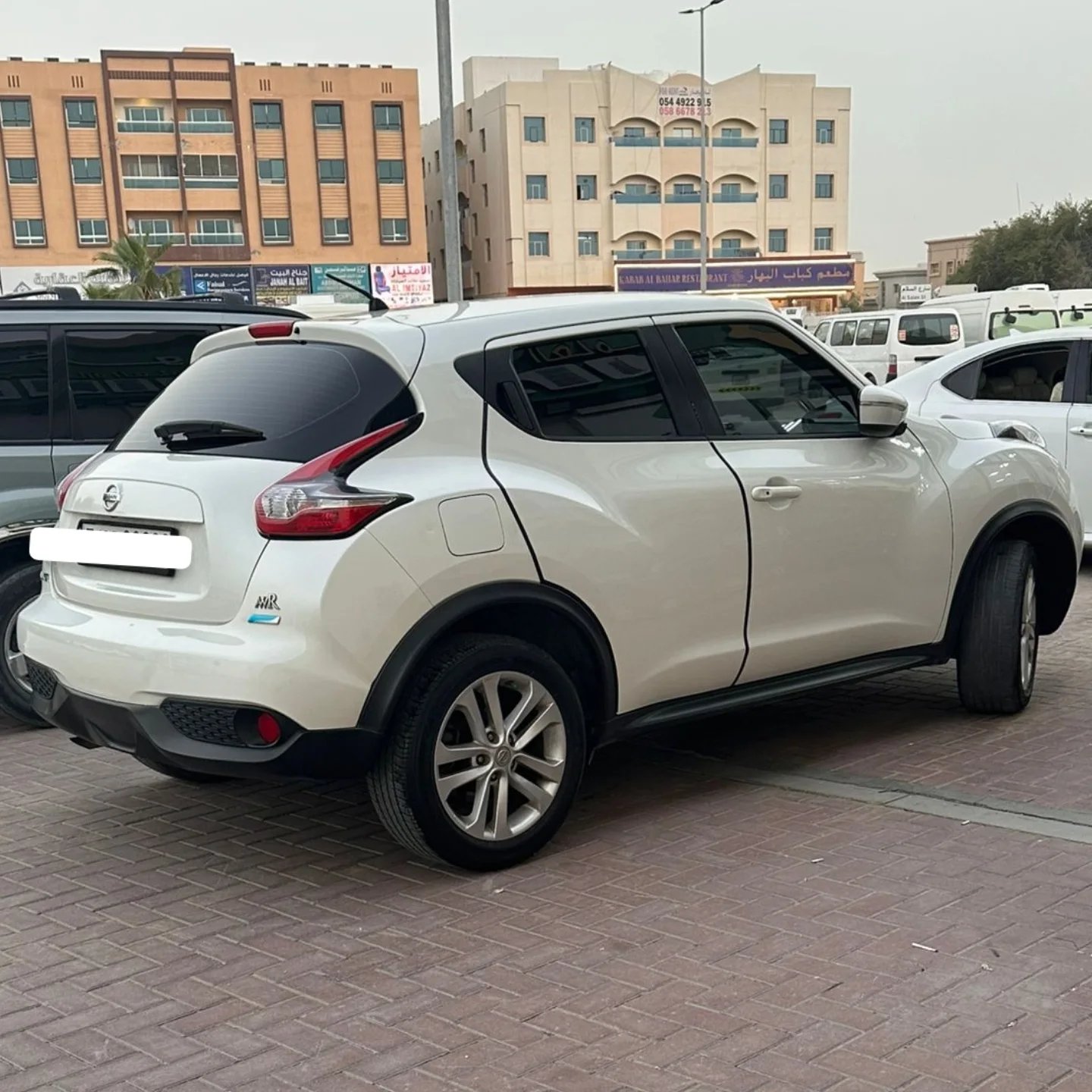 White Nissan Juke SUV parked in a parking lot. The car is facing towards the left side of the image and is positioned in the