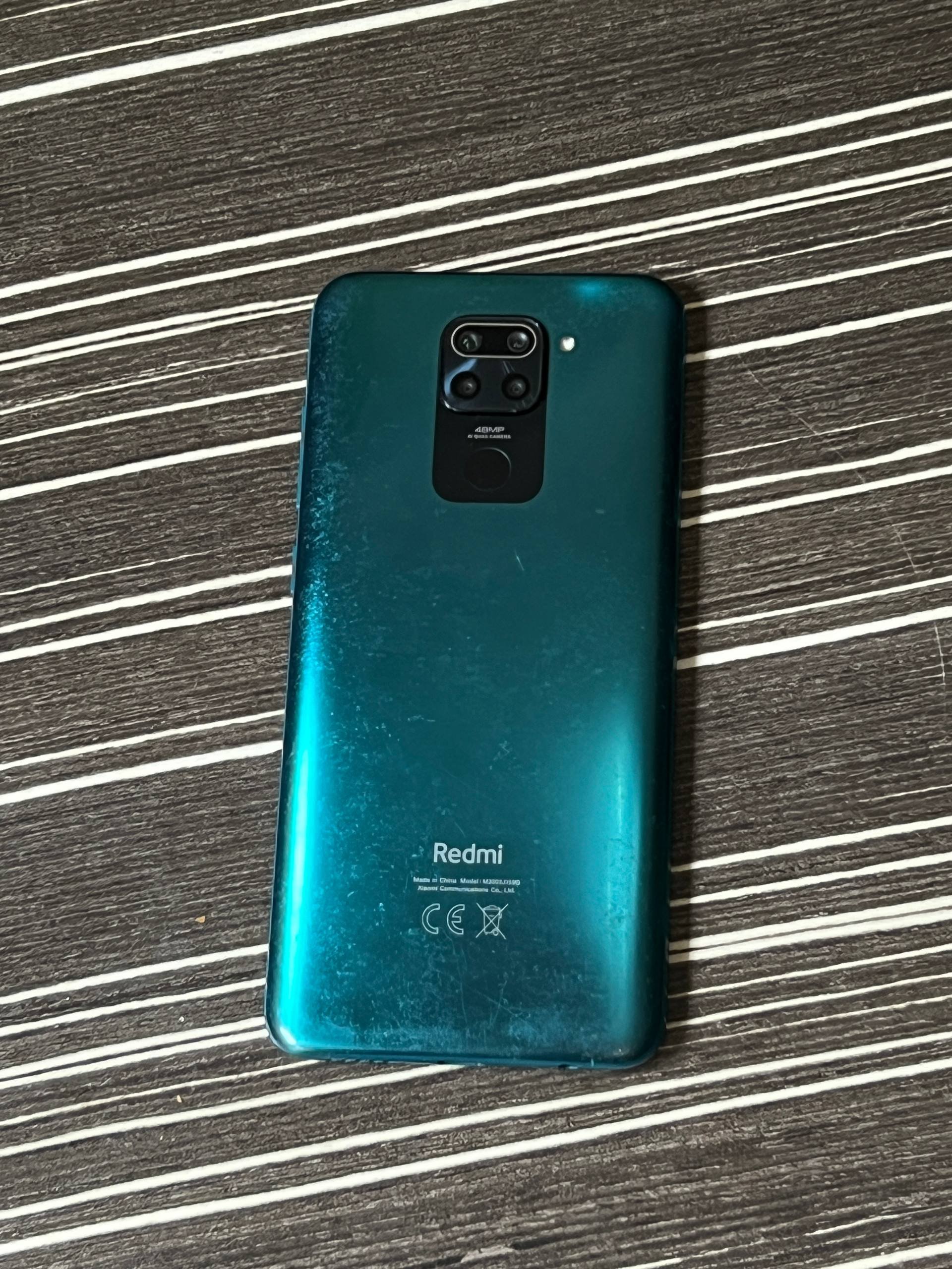 Back of a Xiaomi Redmi Note 9 Pro smartphone. The phone is lying on a black and white striped surface. The back of the phone